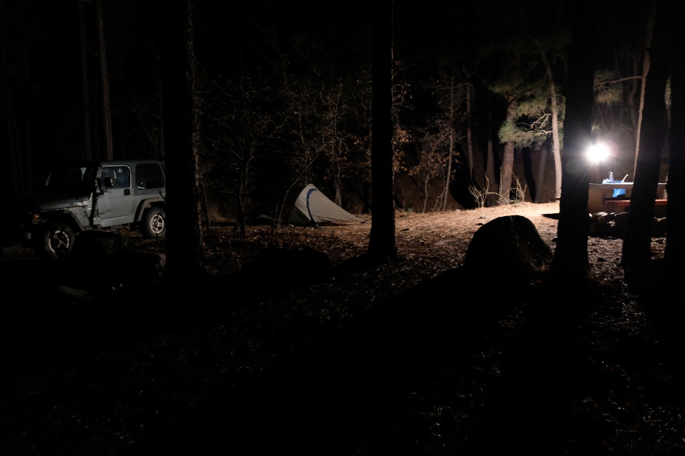 The camp sight in the evening, lit by a lantern.