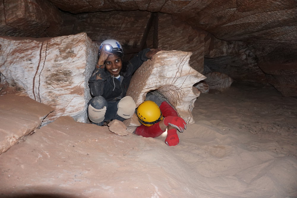 Eshani helping a larger caver get through the crawl.