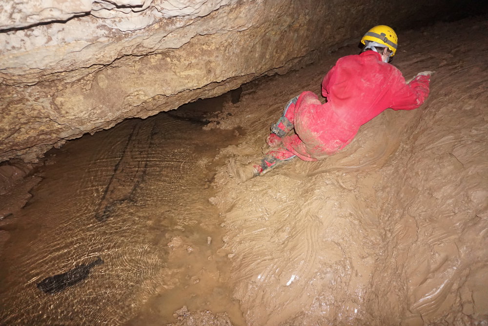 A caver almost sliding into the water.