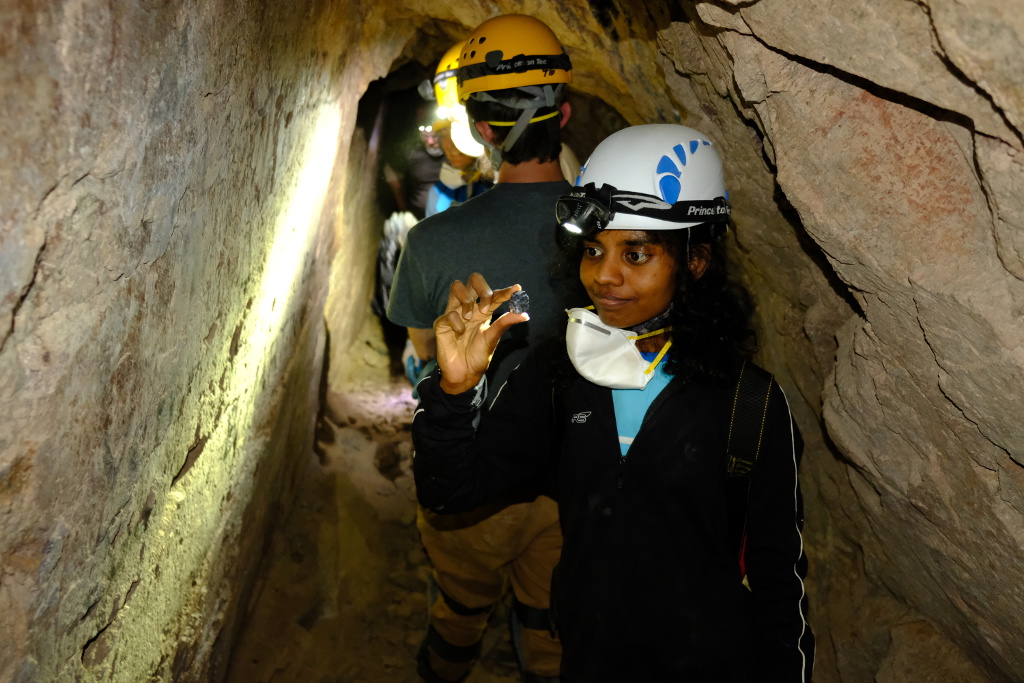 Eshani looking at a rock she found in the upper passage.
