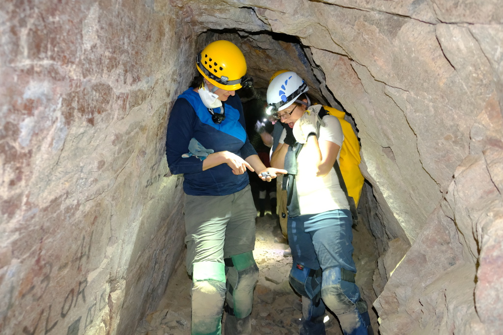 A couple cavers looking at a rock.